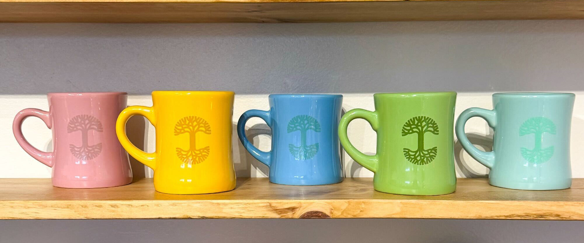 Five colorful mugs on a shelf.