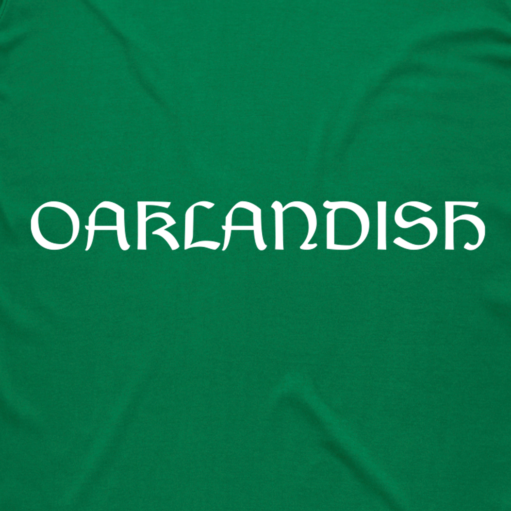 Green background displaying "OAKLANDISH" in stylized white text, evoking a Celtic-themed design from the Eire Tee by Oaklandish.