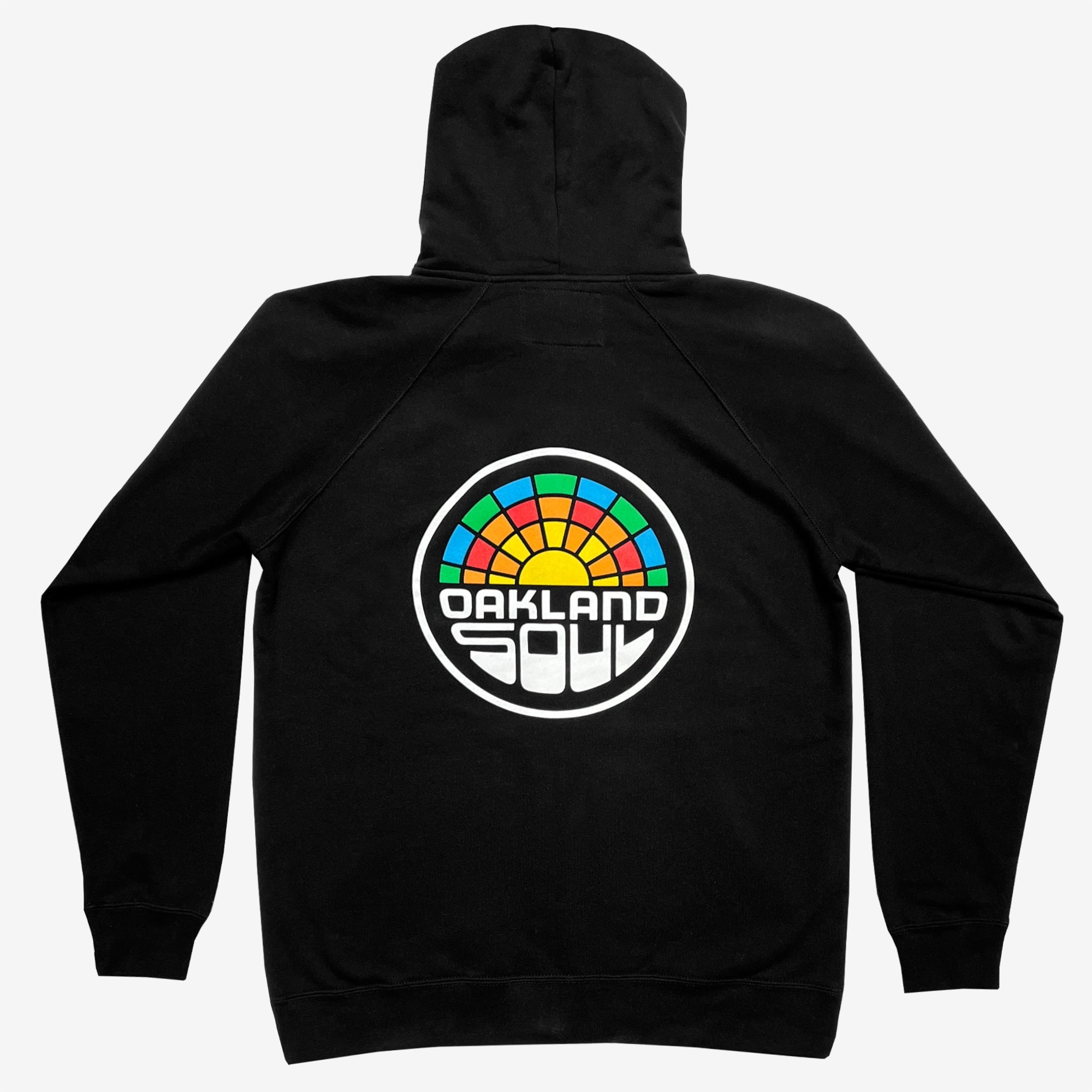 Oakland Soul Logo Zip hoodie, a black unisex zip-up featuring a striking back design with a circular, colorful logo. The logo showcases a semi-circle of multi-colored stained glass patterns above the text "OAKLAND SOUL SC" in bold, white, block letters inside a black border. Laid flat to display the back design prominently, this hoodie embodies social good and community spirit. Brought to you by Oakland Roots SC.