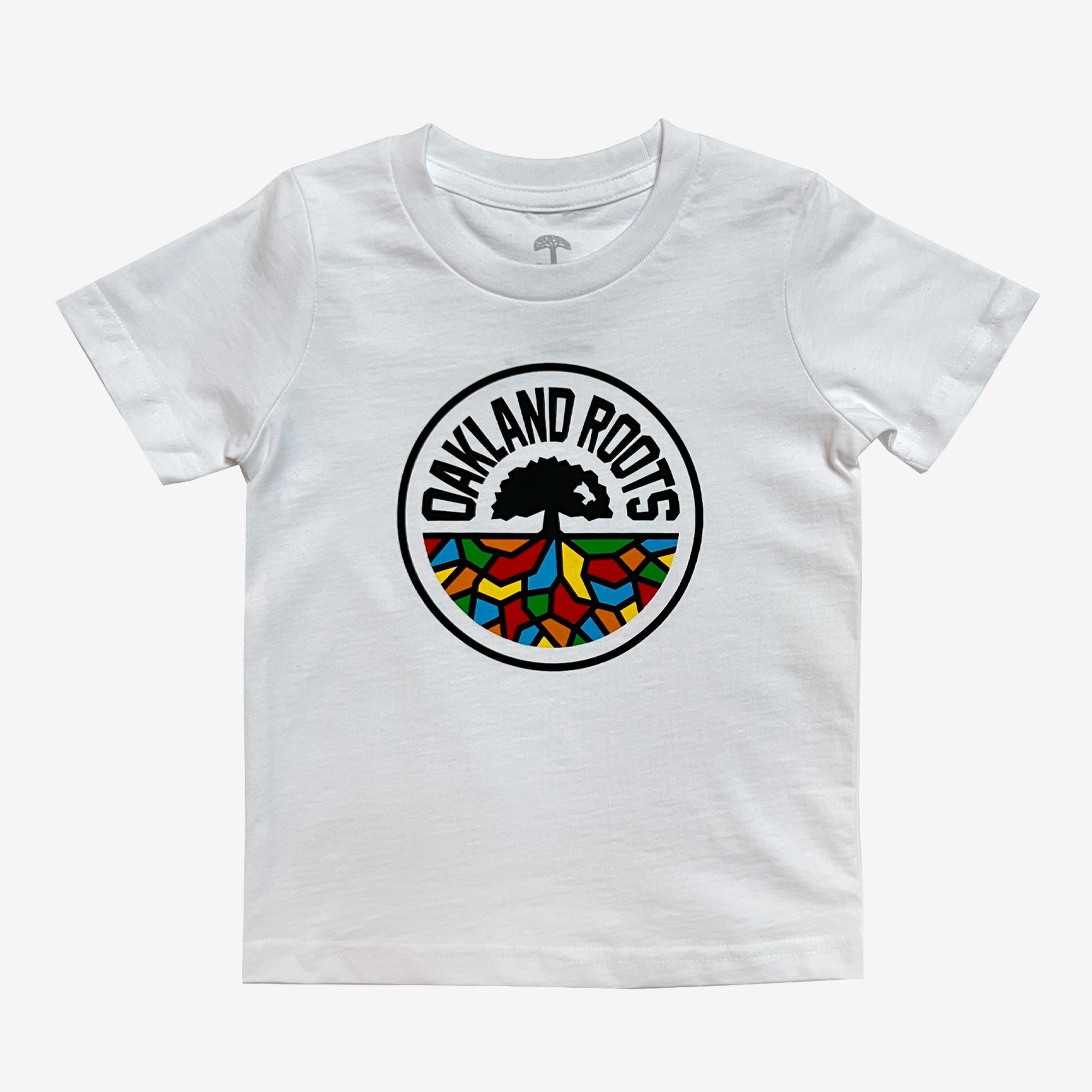 The Toddler Oakland Roots SC Classic Tee by Oakland Roots SC is a white, short-sleeve t-shirt that showcases the "Oakland Roots" logo at its center. The black tree with roots is surrounded by colorful, stained glass-like sections in red, green, yellow, and blue. Above the tree, "OAKLAND ROOTS" is elegantly arched. It's an ideal choice for any young fan of the Oaklandish sports club.