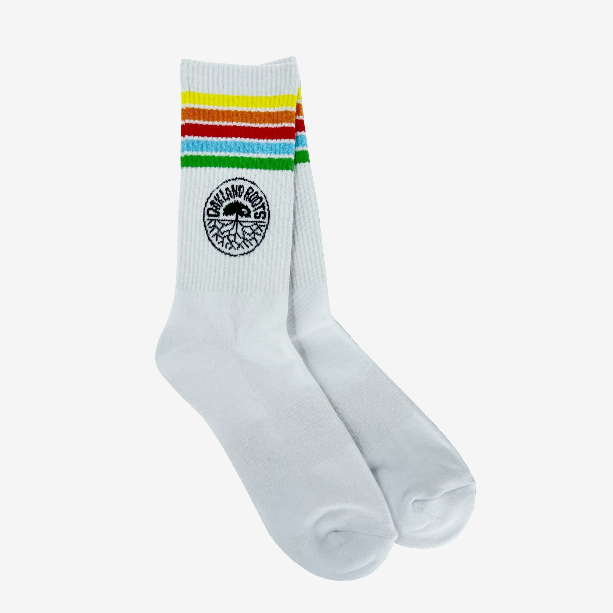 Introducing the Oakland Roots SC Stripes Sock by Oakland Roots SC: White crew socks featuring a striking design at the top with five vibrant horizontal stripes in green, yellow, orange, and red. Below these colorful stripes is a distinct black circular logo that reads "Copeland Projects" surrounding a tree design. Ideal for Sports Club members or devoted Oakland Roots fans, these socks are beautifully showcased against a plain white background.