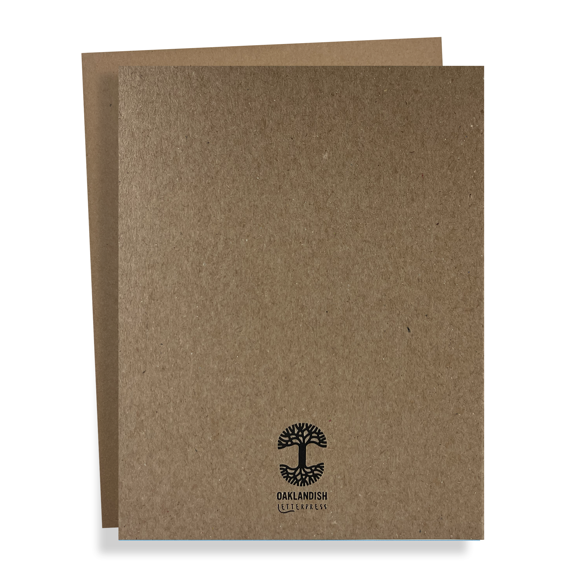 Two brown cardboard folders are stacked, with the one in front slightly overlapping the one at the back. The front folder, known as the Oaklandish New Logo Card by Never Elsewhere, is crafted from recycled brown kraft paper and features a black logo of a tree with roots along with the text "OAKLANDISH" underneath. The overall design is simple and minimalistic.