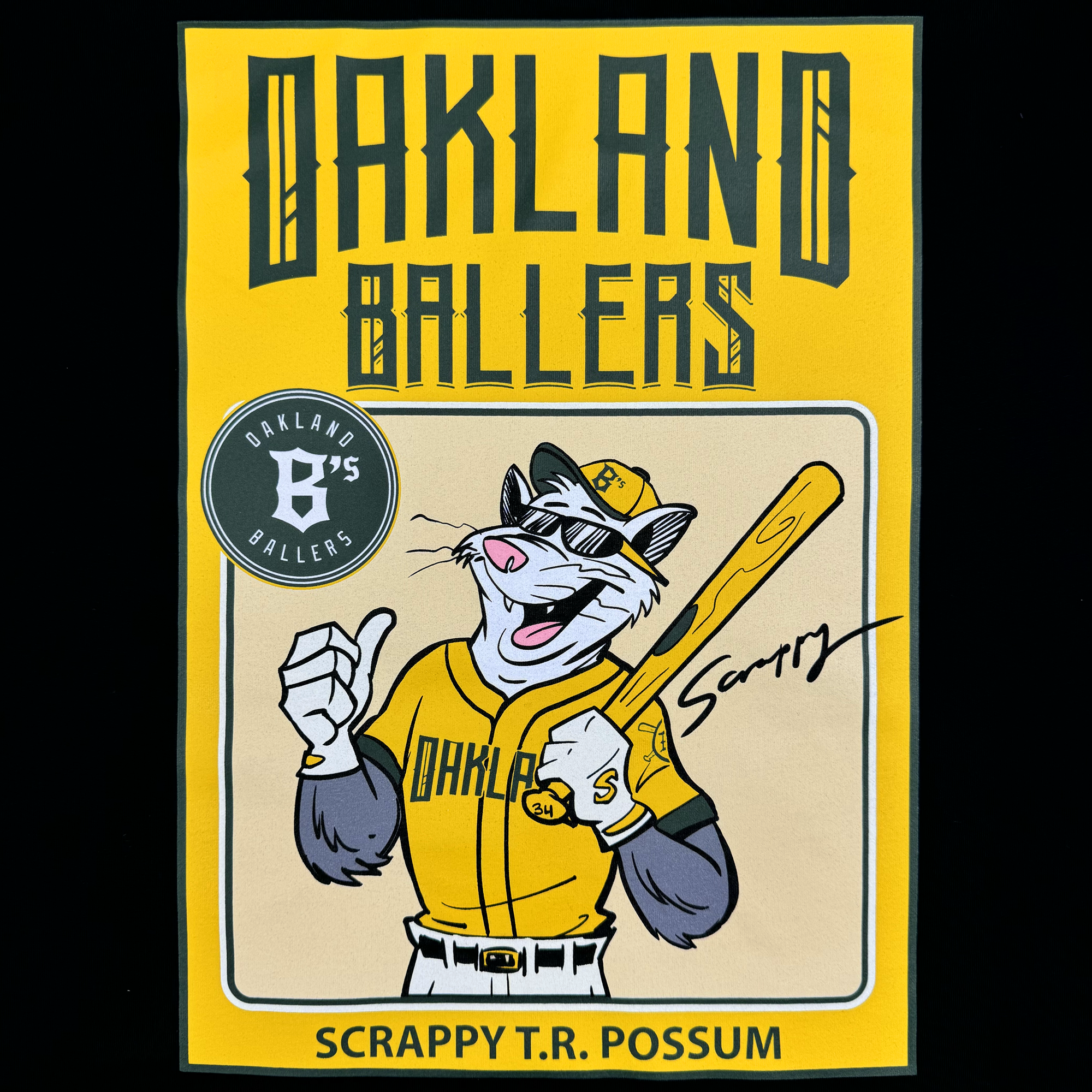 A cartoon possum, echoing the style of Ken Mitchroney, appears on a poster dressed in a baseball uniform from the Youth Scrappy Rookie Tee collection. Sporting sunglasses and a cap, he gives a thumbs-up while proudly wearing the "Scrappy" outfit featuring "Oakland Ballers." A bright yellow background highlights the bold text: "Oakland Ballers" and "Scrappy T.R. Possum.