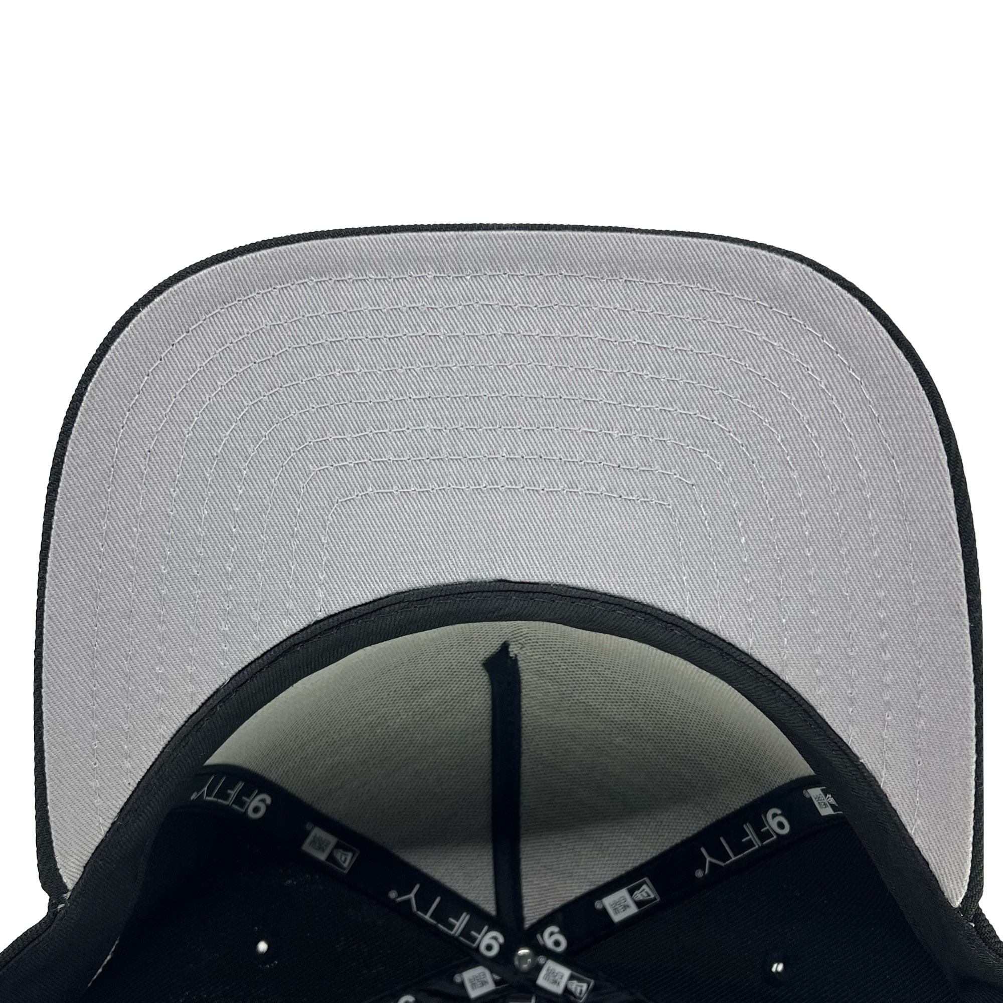 A top-down view of the underside of a black Oakland Ballers New Era Alt Logo 9FIFTY AF Cap with a grey brim. The brim features detailed rows of stitching. The inner seam and size label are visible, indicating it's from the '9FIFTY' series. The internal structure of the hat, including black bands and interior panels, is also clearly seen.