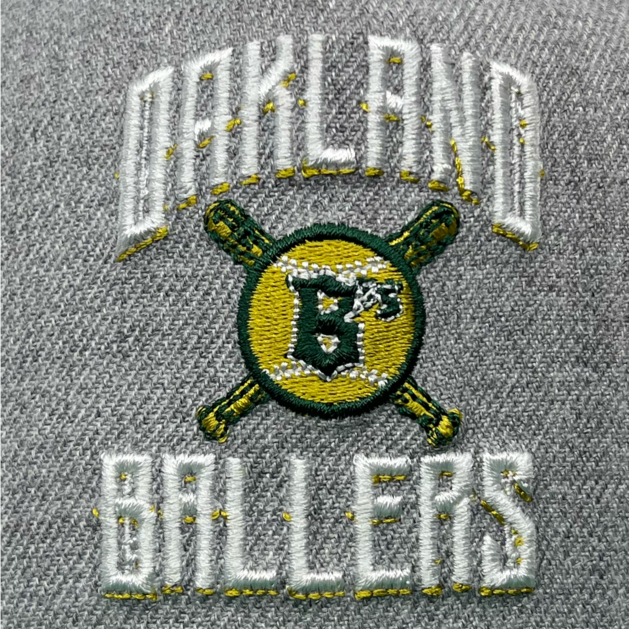 The New Era Oakland Ballers Alt Logo 9FIFTY AF Cap showcases a gray fabric background with an embroidered "Oakland Ballers" logo in white script and yellow accents. The logo features two crossed yellow and green baseball bats behind a green and yellow baseball with "B's" stitched in the middle, symbolizing Oakland's new pro baseball team.