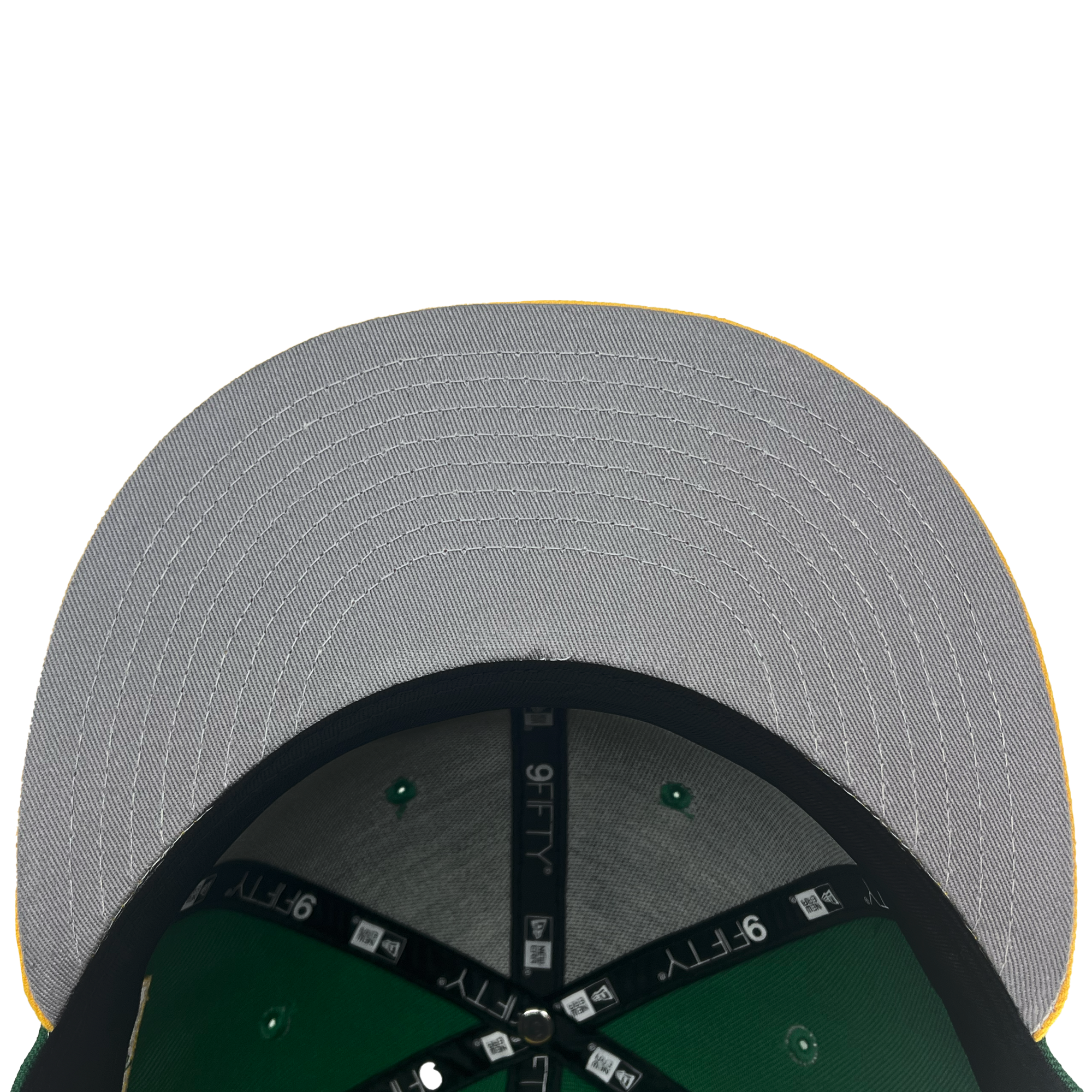 A close-up view of the underside of a New Era Oakland Ballers 9FIFTY Cap. The brim is grey with visible stitching in concentric circles, while the inside is green with a black band and white "9FIFTY" logos imprinted on it. A partially visible green and white label represents the Oakland Ballers, the city's new pro baseball team.