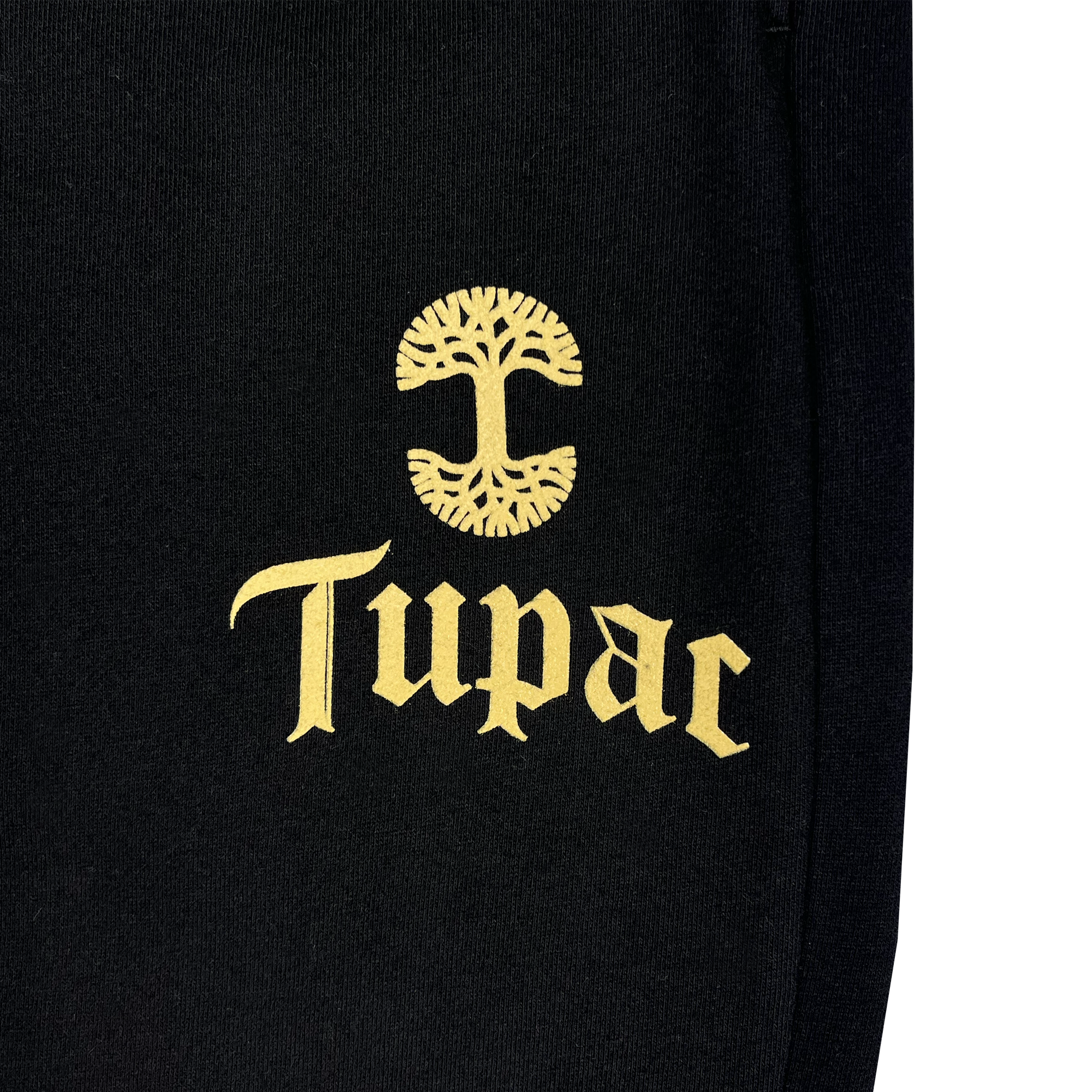 The Bless Jogger by Oaklandish showcases a black fabric adorned with the name "Tupac" in ornate gold text beneath a stylized gold tree design that reflects Oakland's cultural influence. The tree is distinguished by its mirrored, symmetric branches and roots, creating a rounded shape. This piece emphasizes the distinctive collaboration between Oaklandish and Tupac.