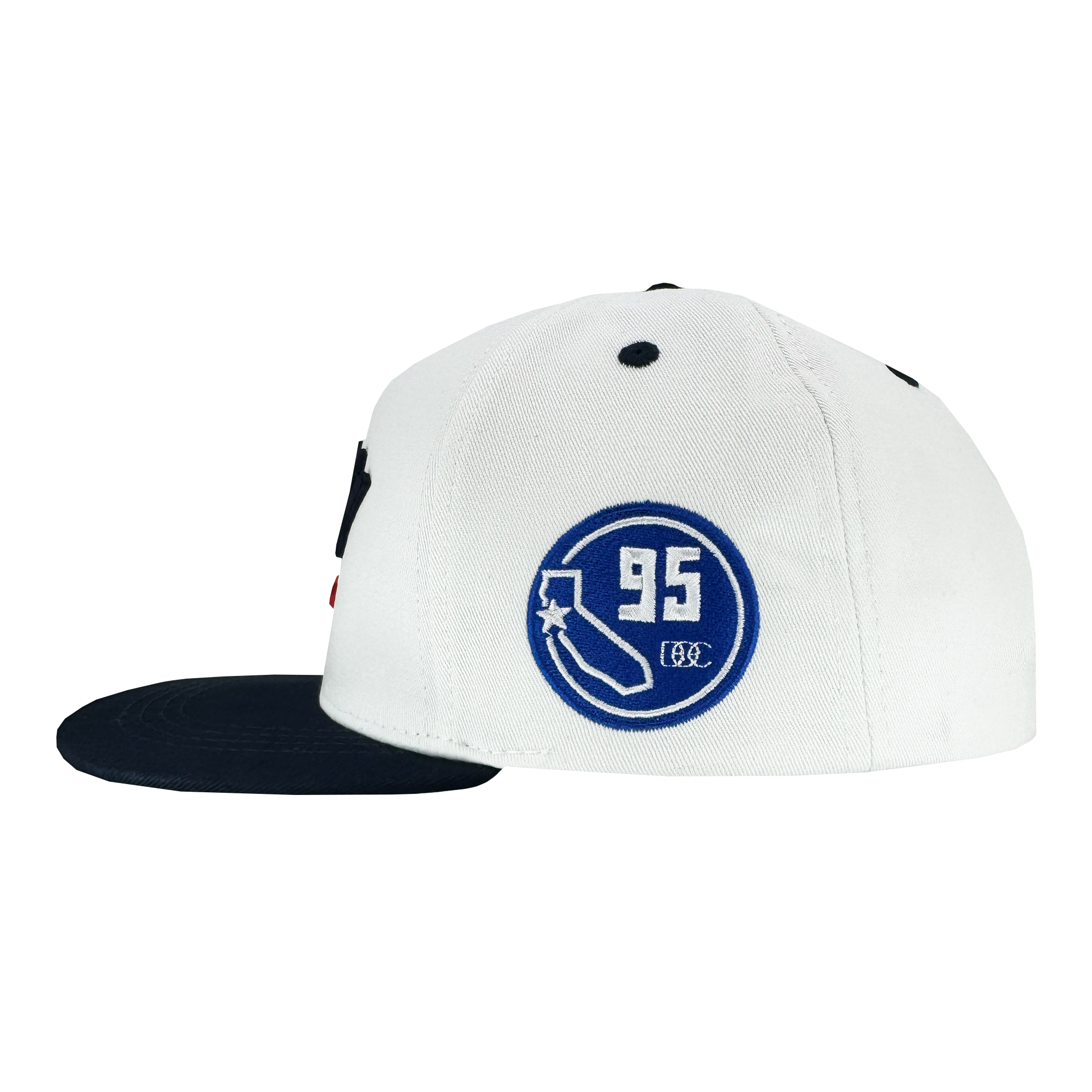 The Bay Bridge Snapback by DOC from Oaklandish is a white hat with a black brim, featuring a blue "95" patch with a sock and shoe design on the side. It embodies Bay Area culture with black ventilation holes and subtle texture for added style.