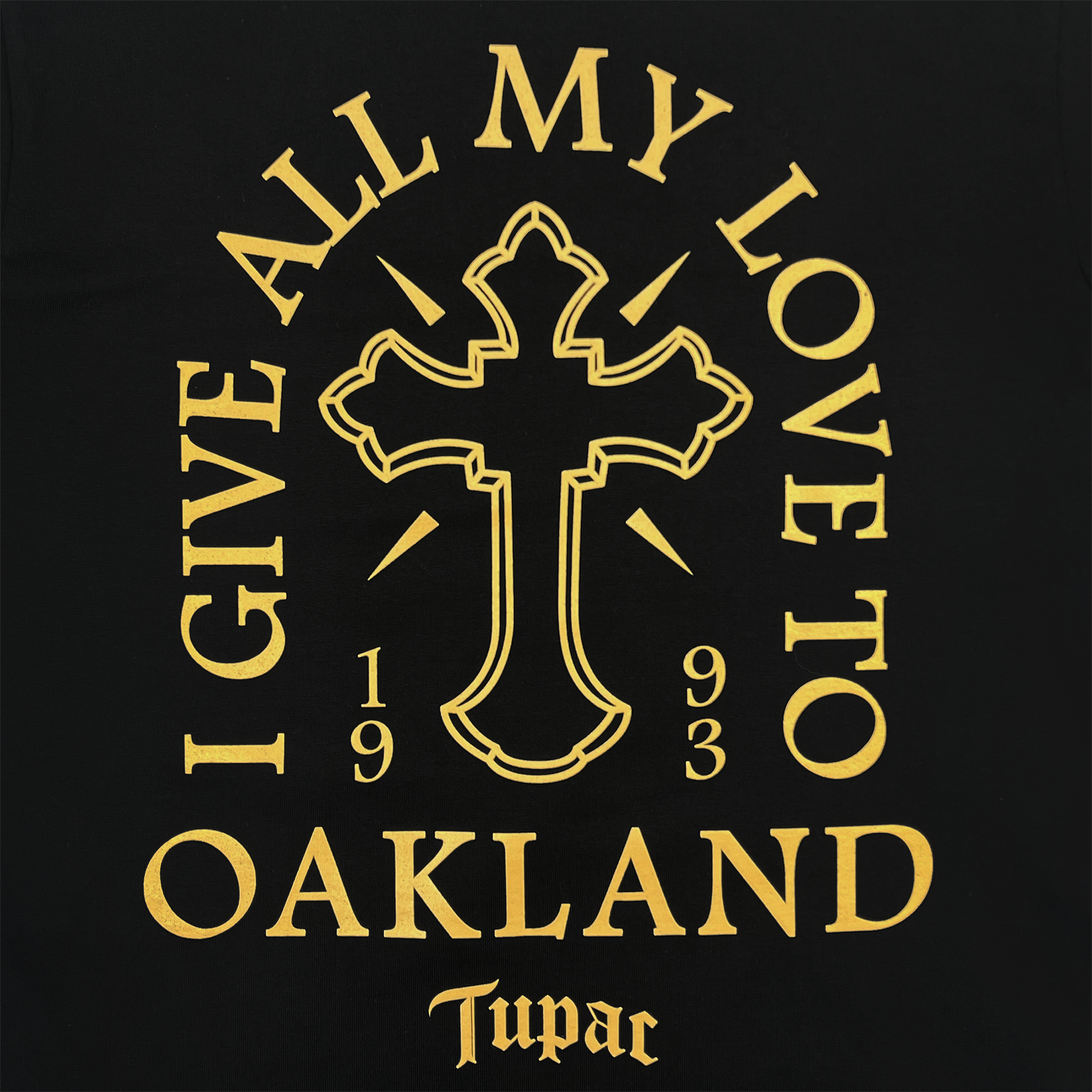 The Double Cross Tee by Oaklandish boasts a black backdrop with a central golden cross. Encircling the design are the words "I GIVE ALL MY LOVE TO," while "OAKLAND" stands prominently below. The year "1993" flanks either side of the cross, and at the bottom, "Tupac" is inscribed in a stylized font that captures both Oakland's hip-hop essence and the signature Oaklandish vibe.