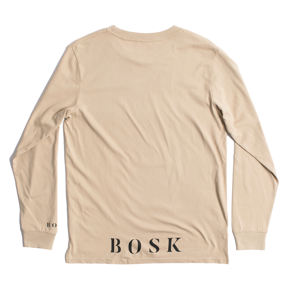 The "Rising Sun LS Tee" by BOSK is a beige long-sleeve t-shirt with a minimalistic design, featuring "BOSK" boldly printed in black on the lower back and "BO" on the sleeve. Made from 100% cotton, this classic fit shirt is displayed laid flat to highlight its back view.