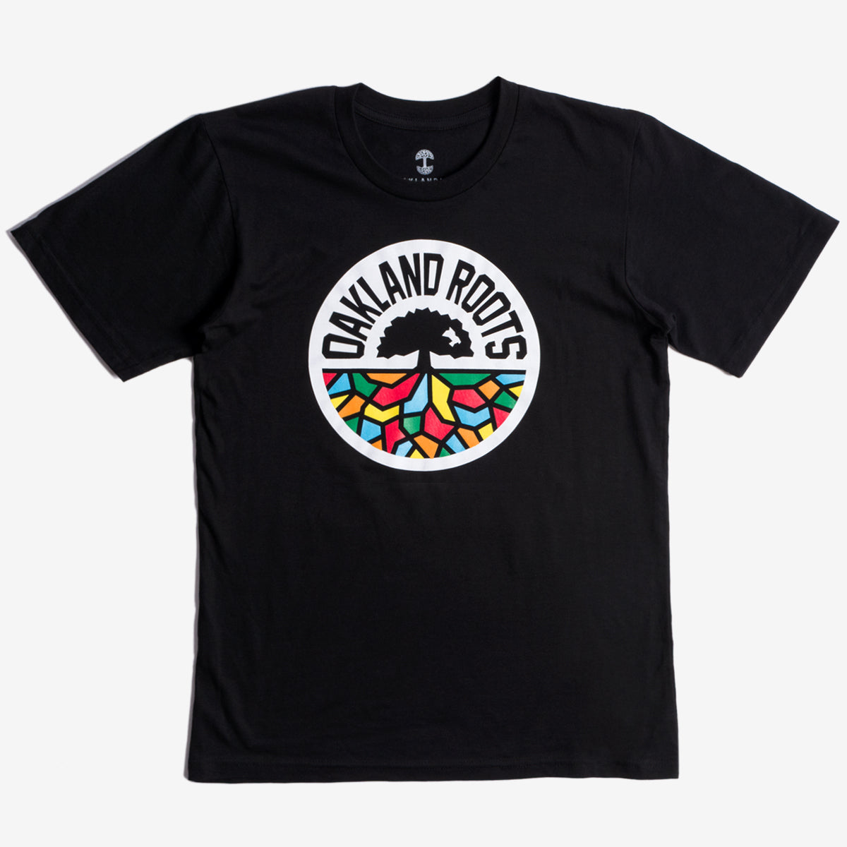 The Oakland Roots SC Classic Tee by Oakland Roots SC is a black t-shirt featuring a circular logo in the center. The logo displays a black tree encircled by the text "OAKLAND ROOTS" in white. Beneath the tree's roots, you'll find colorful geometric shapes in red, green, yellow, and blue, symbolizing the social good values of Oakland Roots Sports Club.