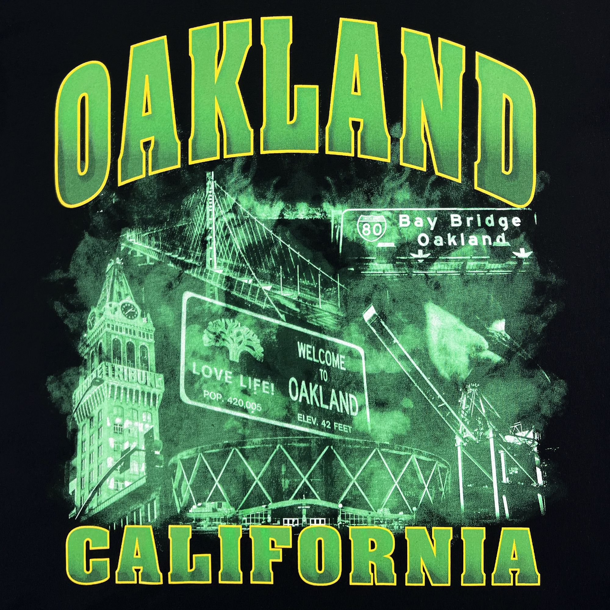 The Montage Tee by Oaklandish showcases a striking image with "Oakland California" boldly displayed in large green and yellow letters. Below, detailed graphics of Oakland landmarks like the Bay Bridge, the Welcome to Oakland sign, and a cityscape are rendered in green against a black background. This classic fit t-shirt is made from 100% cotton.