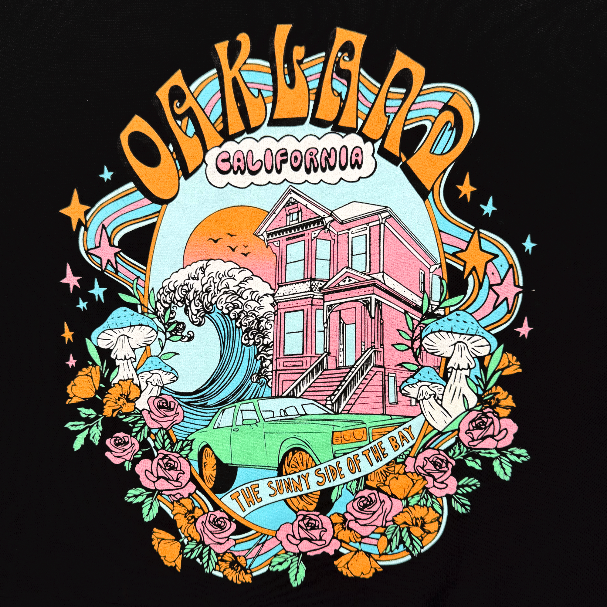 The Women's Oakland Dream Crew by Oaklandish is a cozy sweatshirt featuring a vintage-style illustration with "Oakland, California" text, a pink Victorian house, turquoise car, ocean wave, orange roses, mushrooms, and "The Sunny Side of the Bay" banner with stars. Available in women's sizing.