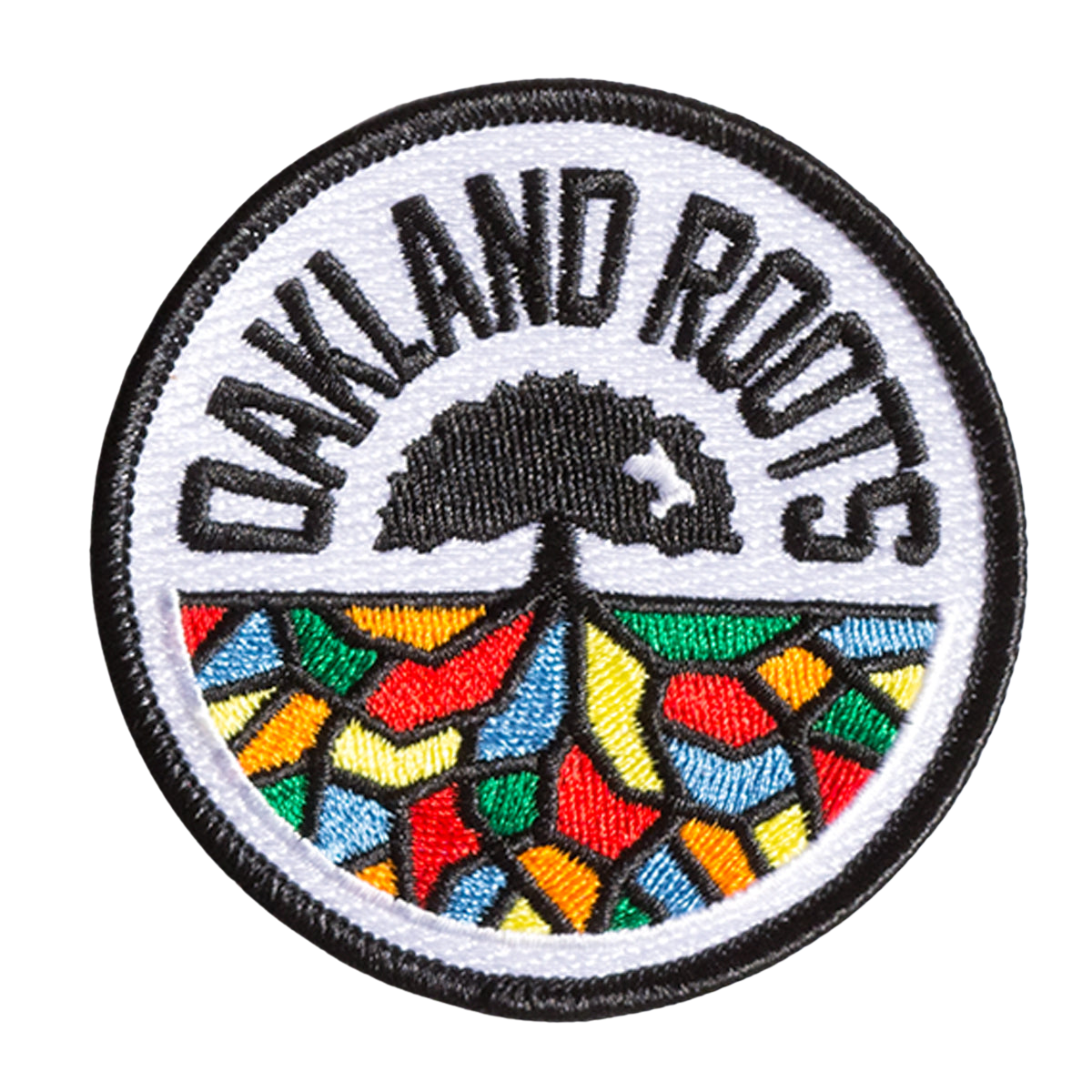 The Oakland Roots SC Patch, crafted by Oakland Roots SC, is a circular embroidered iron-on accessory featuring a black-bordered white background. "OAKLAND ROOTS" is inscribed in black at the top, framing an image of a tree. Beneath the tree, the roots are depicted as a vibrant mosaic with segments in red, orange, yellow, green, and blue—ideal for fans of the Oakland Roots Sports Club.