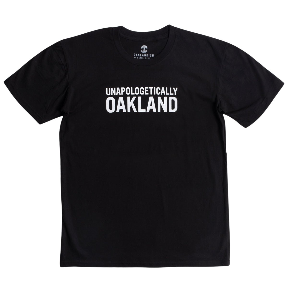 The Unapologetic Tee by Oaklandish is a black men's T-shirt with bold white "UNAPOLOGETICALLY OAKLAND" text on the front, made from 100% cotton, featuring the "OAKLNDISH" label inside the neck, and shown against a plain white background.