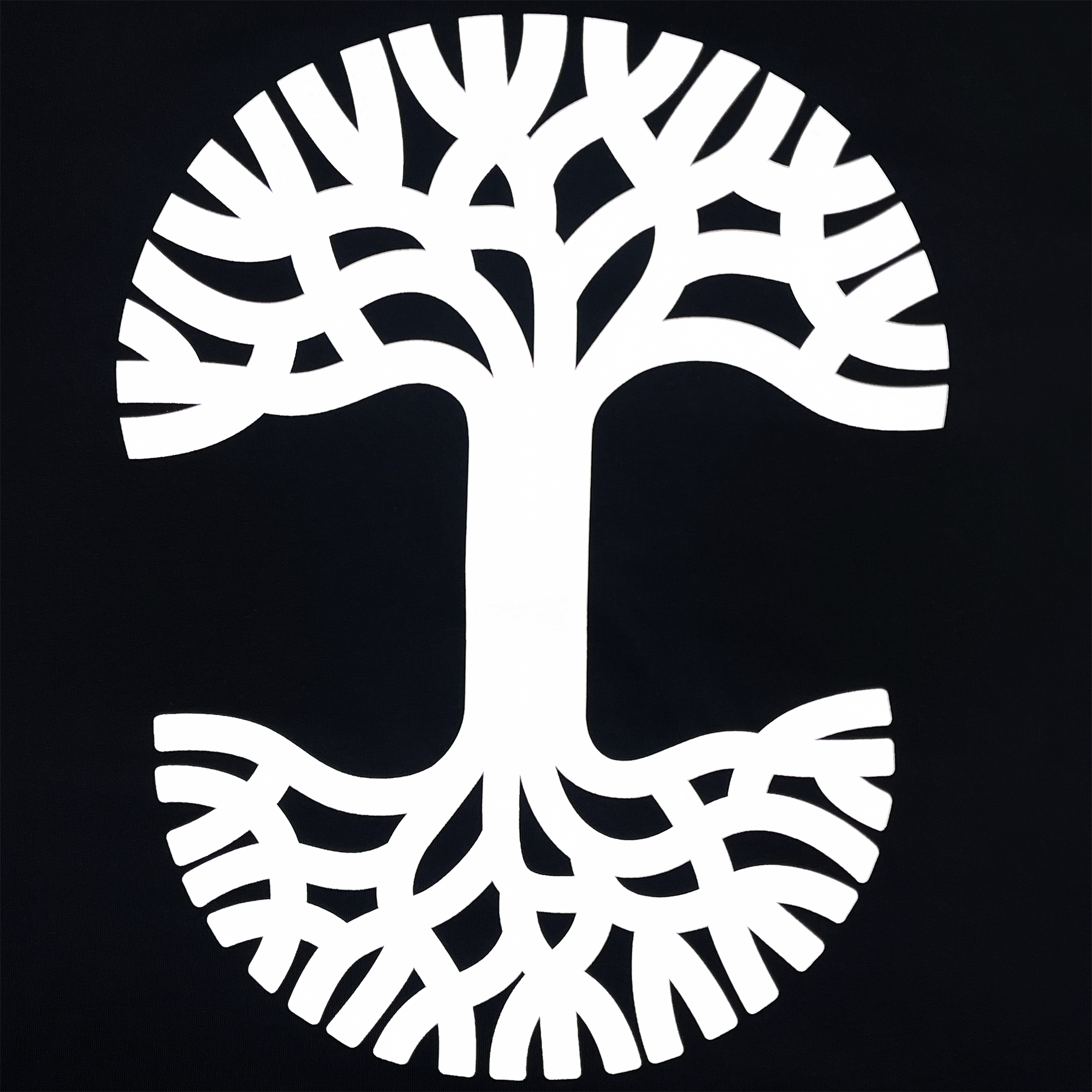 The PacLogo Tee by Oaklandish features a white tree with branching roots, forming a circular design on a black background that captures the essence of their iconic logo. The outward-extending branches intertwine seamlessly while the mirrored roots create symmetry, evoking a sense of unity and completeness.