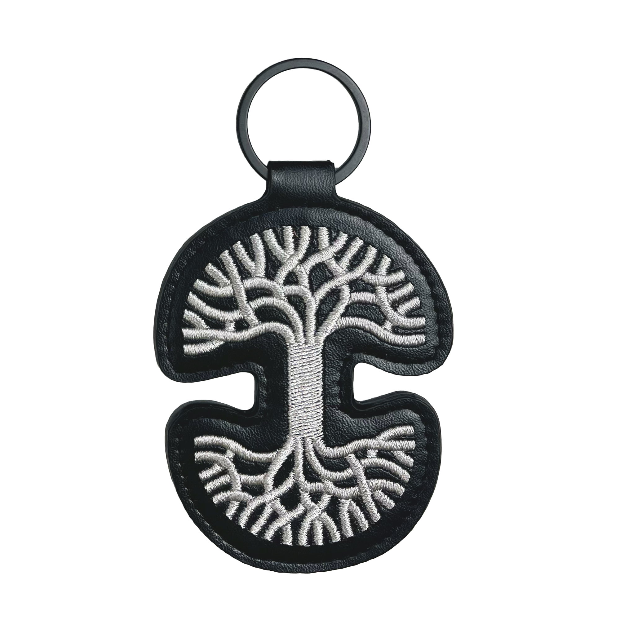 The Oaklandish Logo Keychain features a sleek black PU leather design with an intricate white embroidered tree of life. This curved and symmetrical accessory prominently showcases the iconic Oaklandish tree logo, complete with spreading branches and roots. A metal ring at the top adds both style and functionality to this elegant piece by Oaklandish.