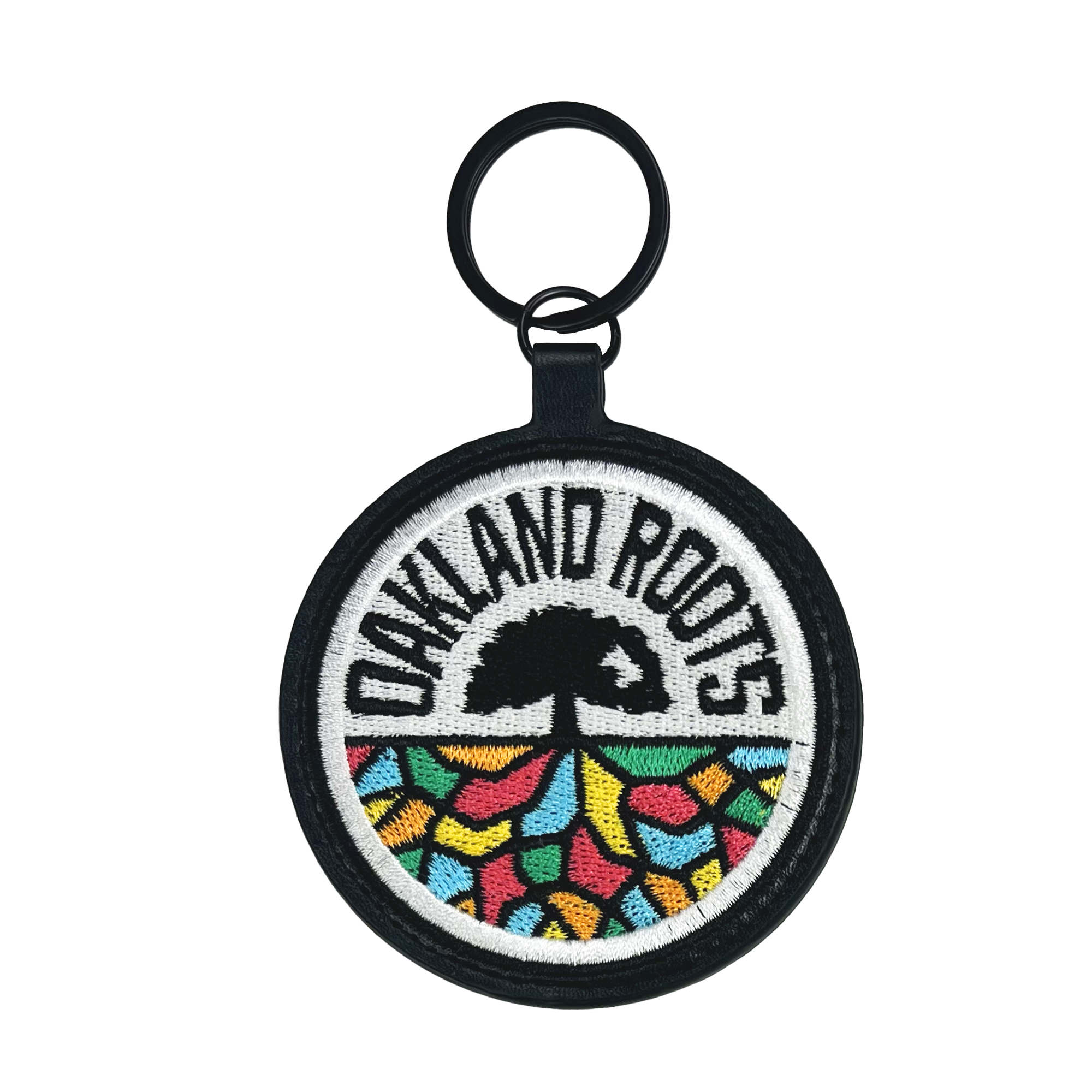 Introducing the Oakland Roots SC Logo Keychain from Oakland Roots SC! This circular keychain proudly showcases the Oakland Roots logo, featuring "OAKLAND ROOTS" in bold black text at the top, a striking black tree silhouette in the center, and vibrant abstract shapes resembling the ground beneath. Celebrate your favorite sports club with this stylish accessory that also supports social good initiatives.