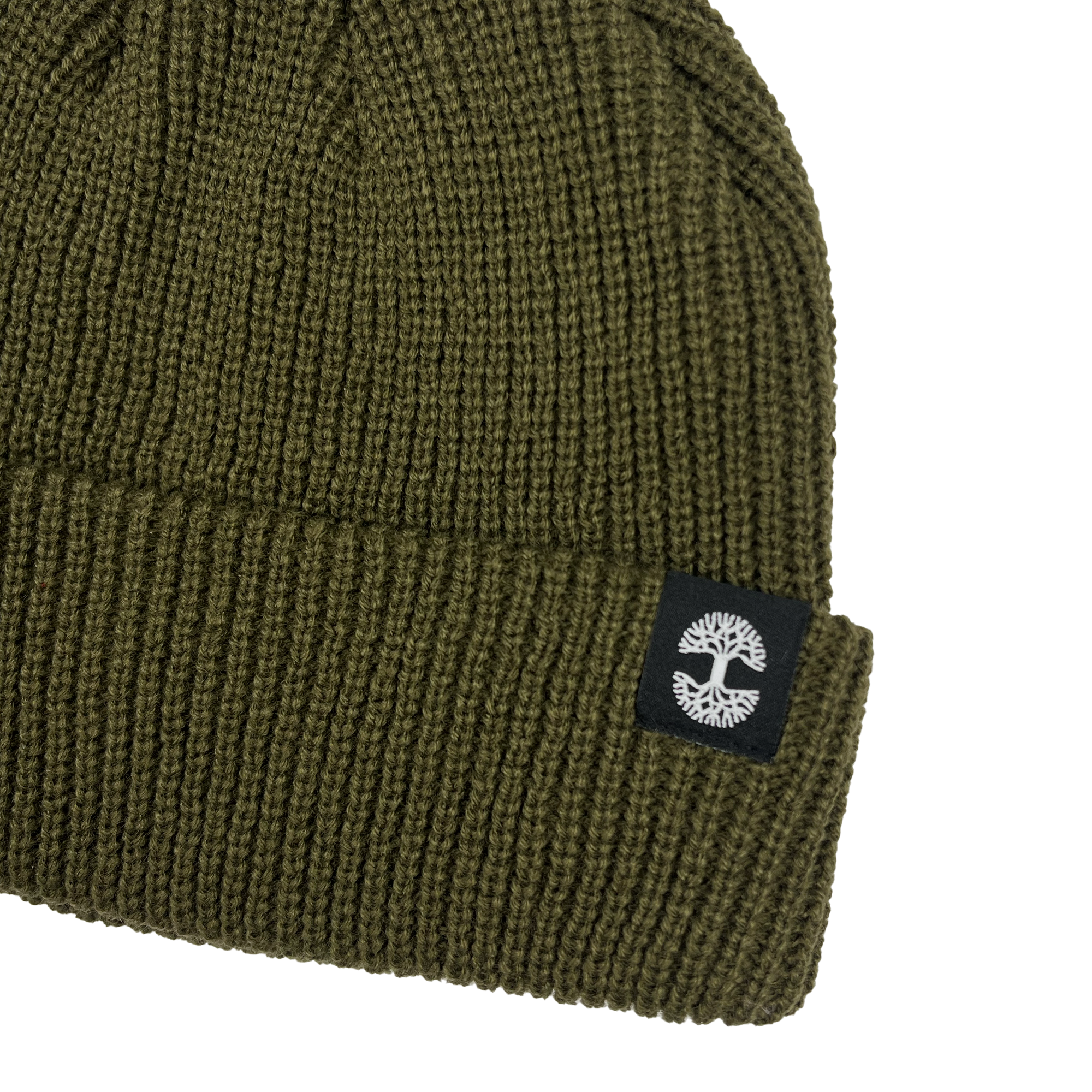 The Ramos Beanie by Oaklandish is an olive green knit hat made from woven acrylic. It showcases a folded brim adorned with a black fabric patch that features a white tree emblem. The beanie has a ribbed texture, contributing to its cozy and warm look.