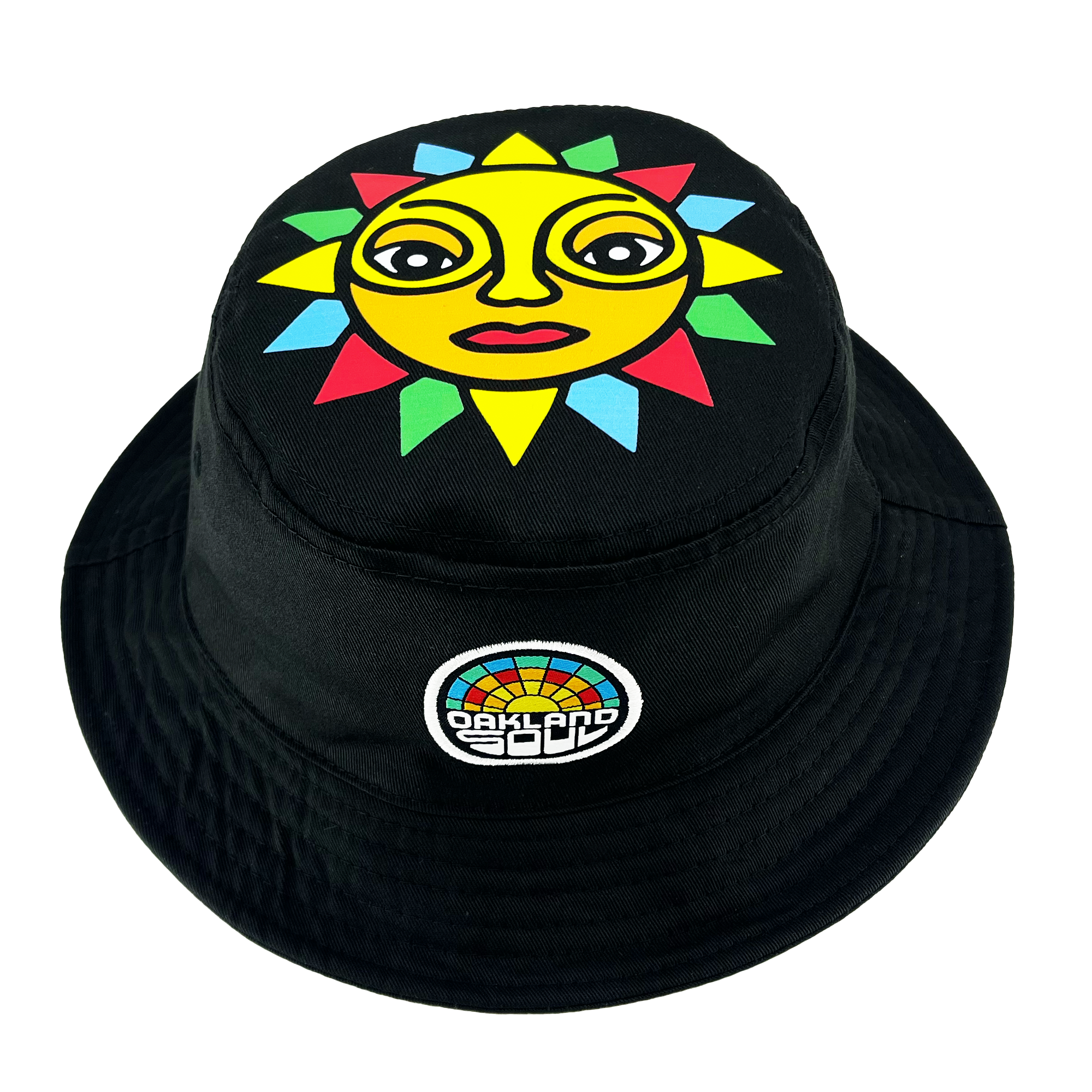 The Oakland Soul & Roots SC Reversible Bucket by Oakland Roots SC is a versatile black bucket hat that showcases a vibrant design on one side. The top of the hat features an illustration of a lively sun with a yellow face, expressive eyes, and multicolored rays. Accompanying the sun, there's a small patch adorned with a colorful semi-circle mosaic pattern and the text "Oakland Roots" below it.