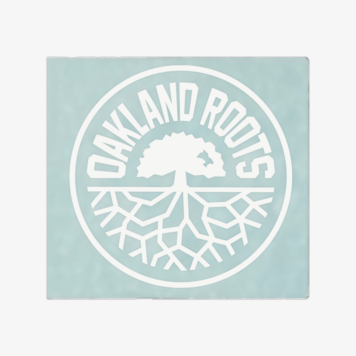 Introducing the Oakland Roots SC Decal - 8", featuring a circular logo with a light teal background. Inside the circle is a striking white illustration of a tree with roots extending outward. Bold, white capital letters spelling "OAKLAND ROOTS" curve along the top inside of the circle, making it an ideal window decal for any sports club fan.