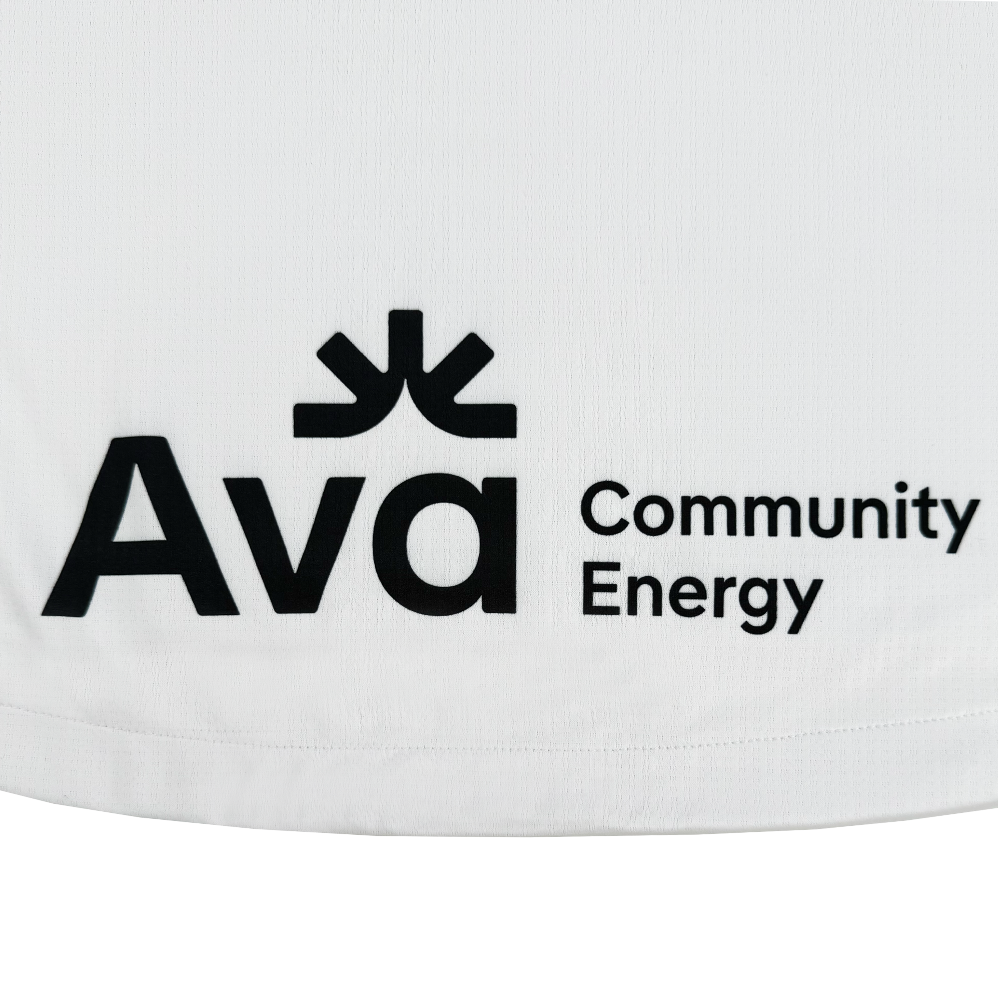 The image displays a white fabric with a black emblem and text, inspired by Oakland sports history. The logo has a stylized symbol above "Ava," with "Community Energy" beside it in smaller black letters. Presented as the Unisex Oakland Roots SC 2025 Second Kit ft. Anthem Blue Cross by Oakland Roots SC.