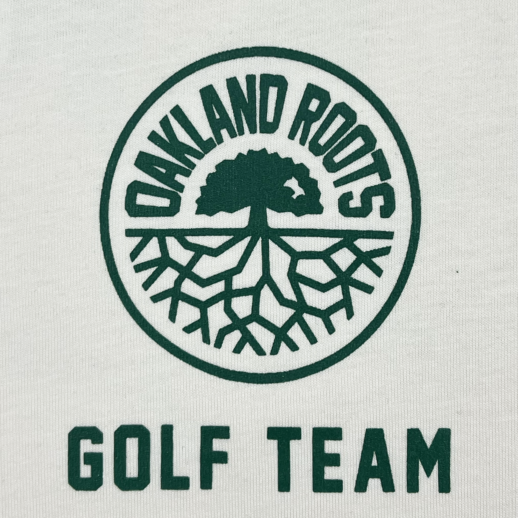 A green circular logo depicting a tree with visible roots is displayed above the words "OAKLAND ROOTS," also in green. Below this logo, "GOLF TEAM" appears in capitalized green letters on a white background. This design, featured on the Oakland Roots SC's Members Only Tee, embodies the club's dedication to social good through sports.