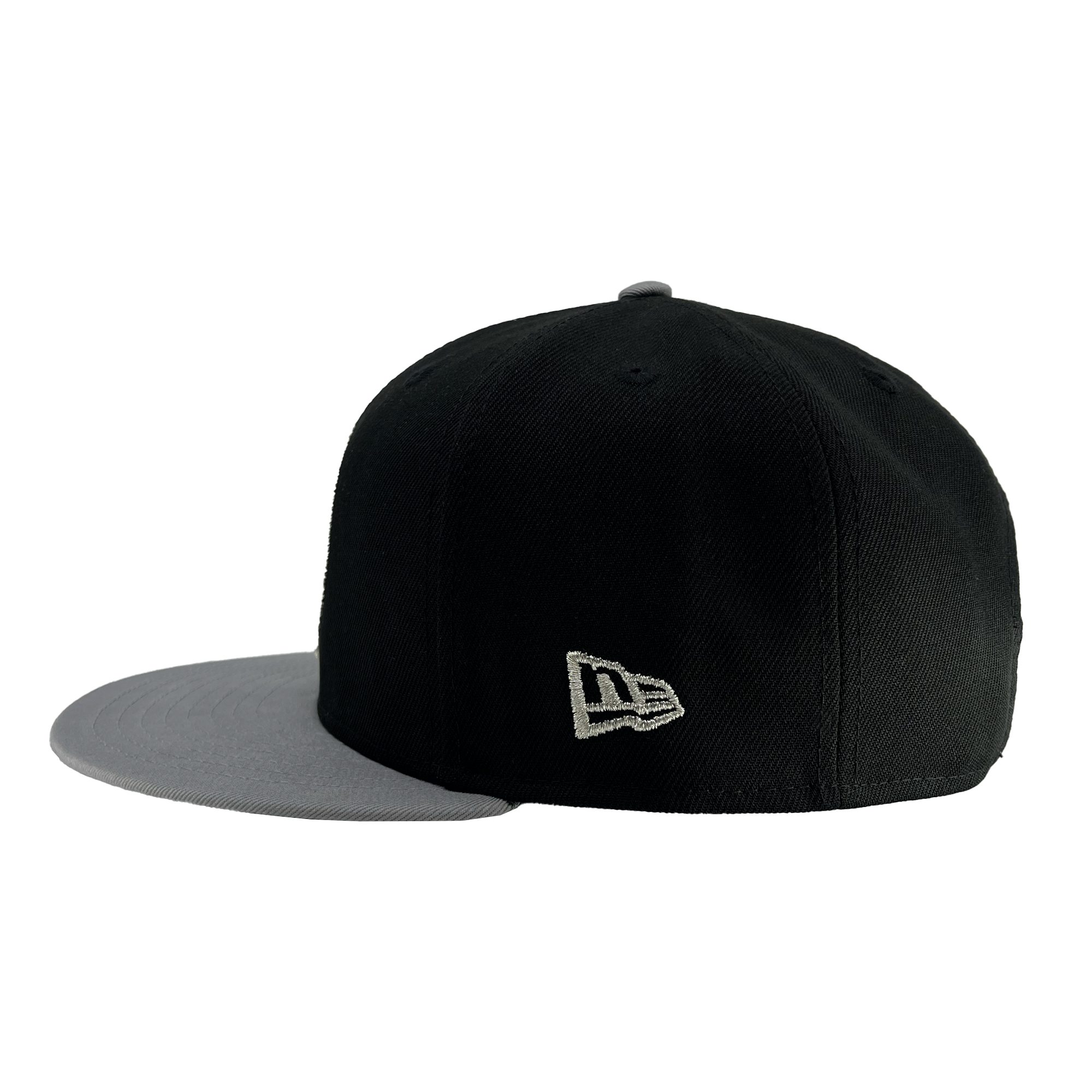 Side view of a black New Era Oakland Roots SC 9FIFTY Cap with a grey brim. The cap features stitched air holes on top for ventilation and an embroidered logo on the side, resembling overlapping letters "N" and "E." The flat brim contrasts with the dark main body, embodying the bold style of the Oakland Roots SC sports club.