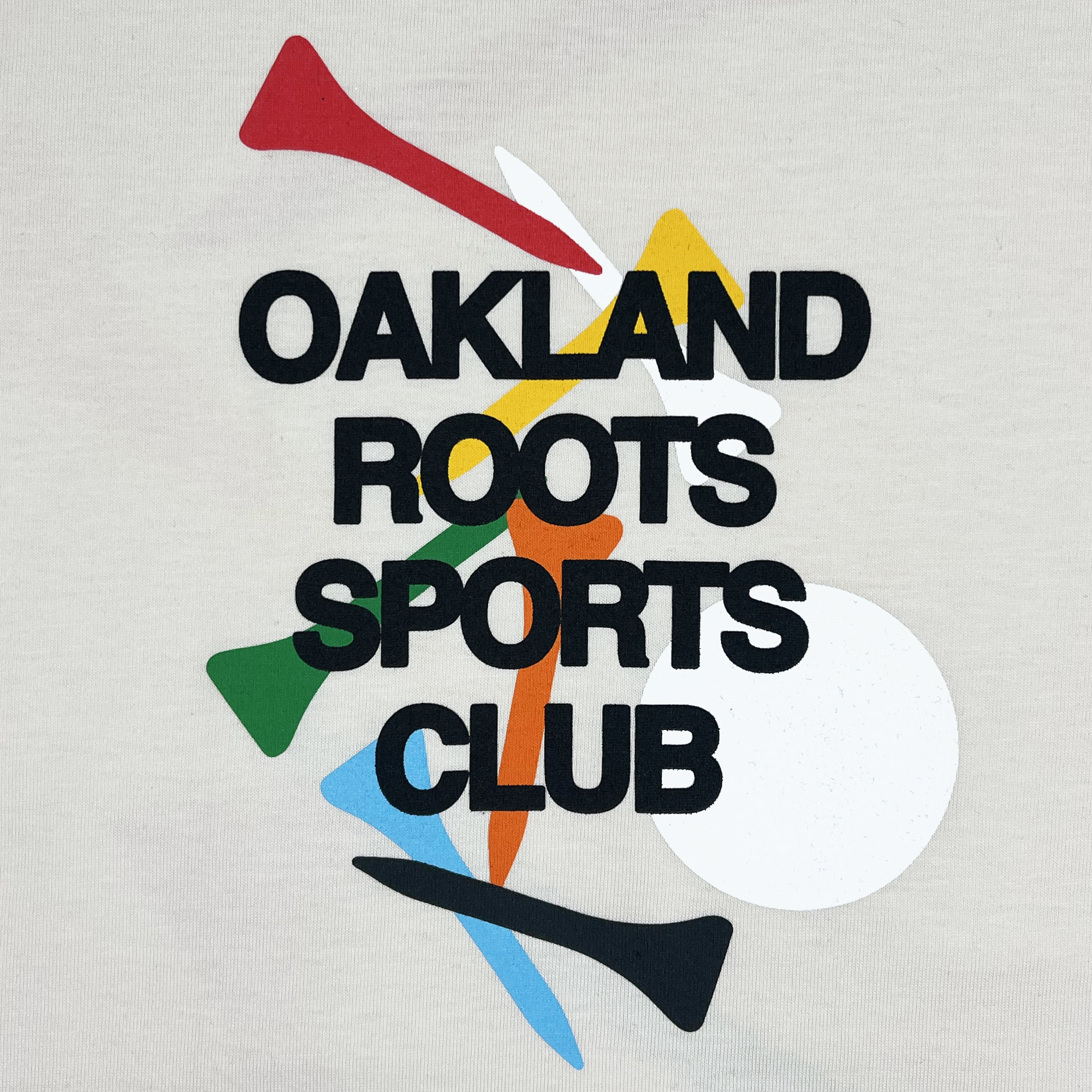 The Tee Time Tee by Oakland Roots SC features a beige background with "OAKLAND ROOTS SPORTS CLUB" boldly printed in black at the center. The design is complemented by abstract shapes in vibrant red, yellow, white, green, blue, and black hues. These shapes include triangles, circles, and elongated forms that create a dynamic pattern on this classic fit t-shirt.