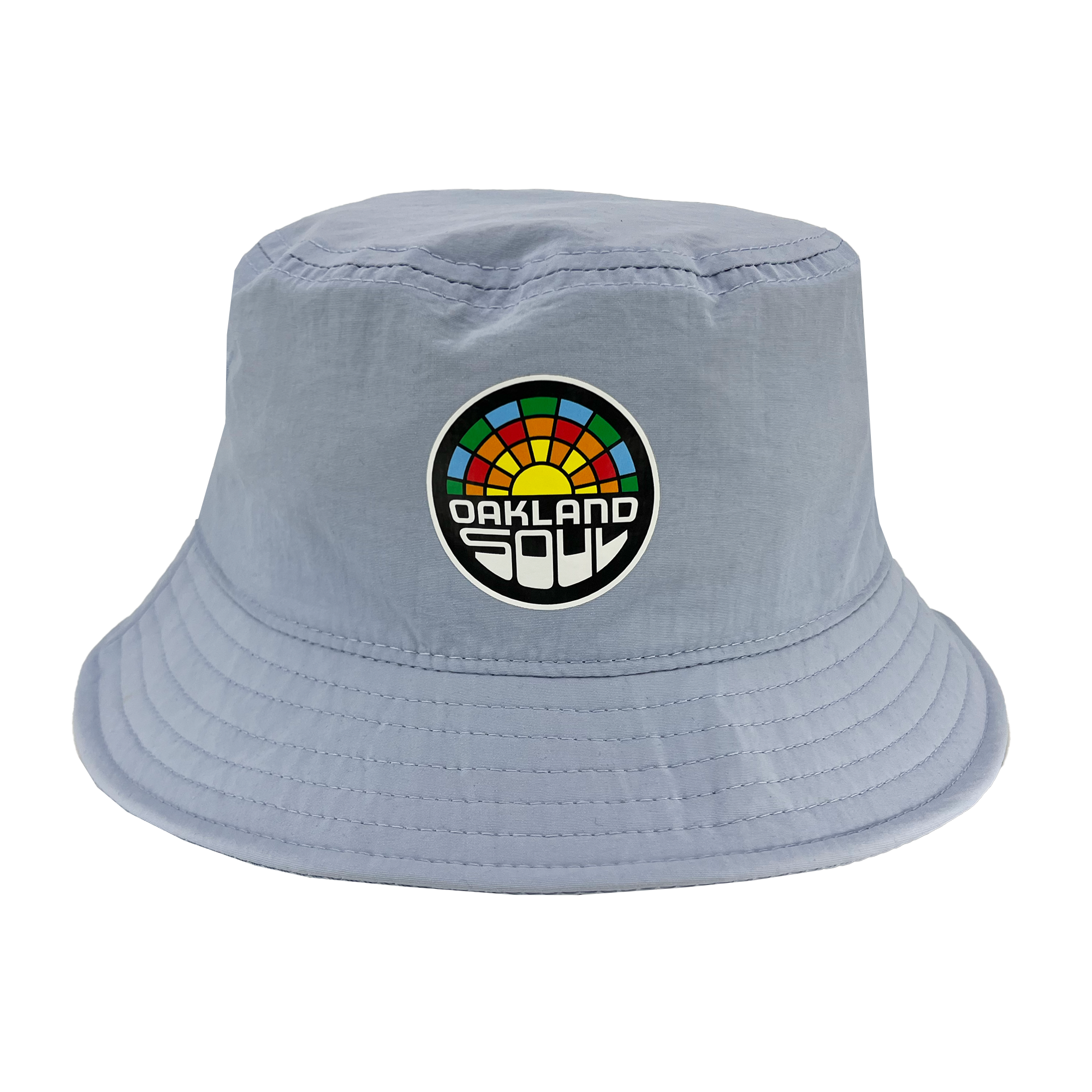 The Oakland Soul Logo Bucket Hat by Oakland Soul is a light blue accessory adorned with a colorful rainbow patch and the words "Oakland Soul" in bold white and black font on the front. Inspired by Oakland's women's soccer team, this hat features a soft, unstructured brim with visible stitching around the edges.