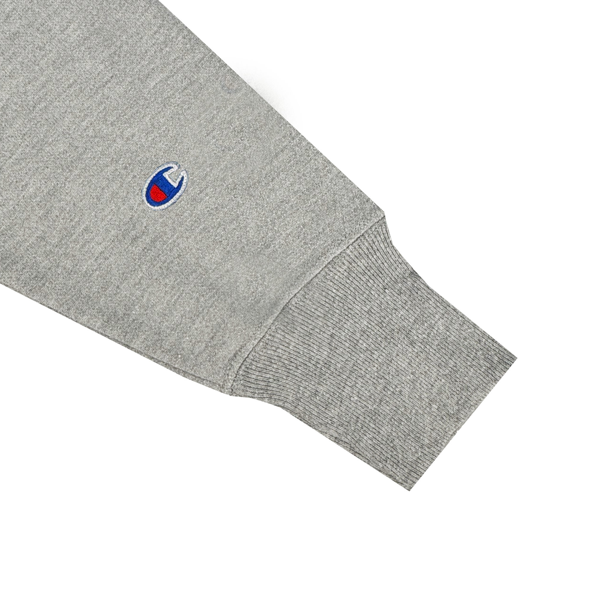 Close-up of a sleeve on the Champion X Oakland Soul Wordmark Hoodie, showcasing a ribbed cuff and fleece-like texture. Near the cuff, an embroidered blue and red logo represents Oakland Soul's vibrant spirit from the USL W-League. The sleeve edge curves slightly at the seam.