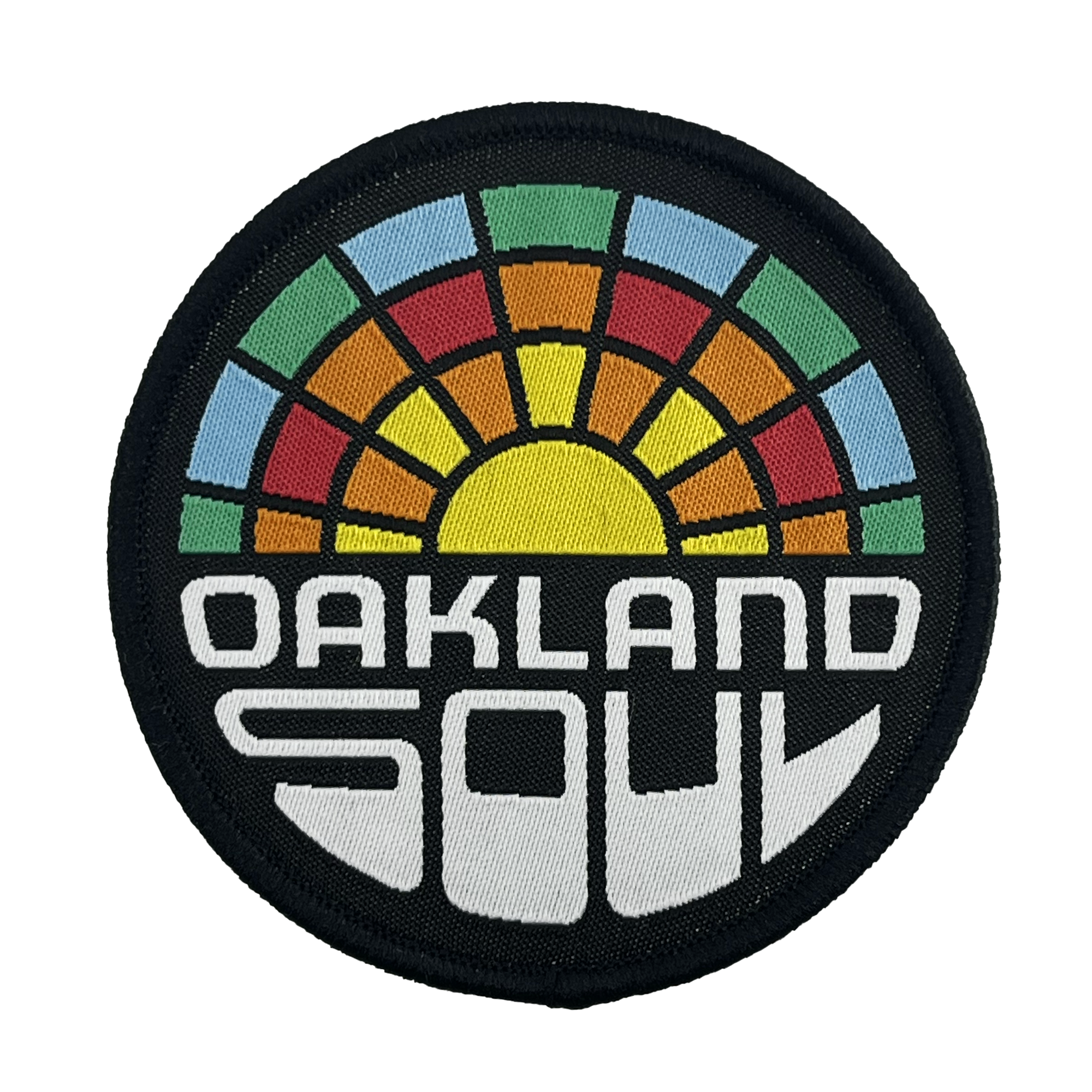 The Oakland Soul Patch by Oakland Soul features a circular design with a black border and a stylized horizon, showcasing a semicircle of multicolored sunrays in green, orange, red, and blue. The bottom half boldly displays "OAKLAND SOUL" in white futuristic font. This embroidered iron-on patch symbolizes the Oakland Roots Sports Club's dedication to social good.