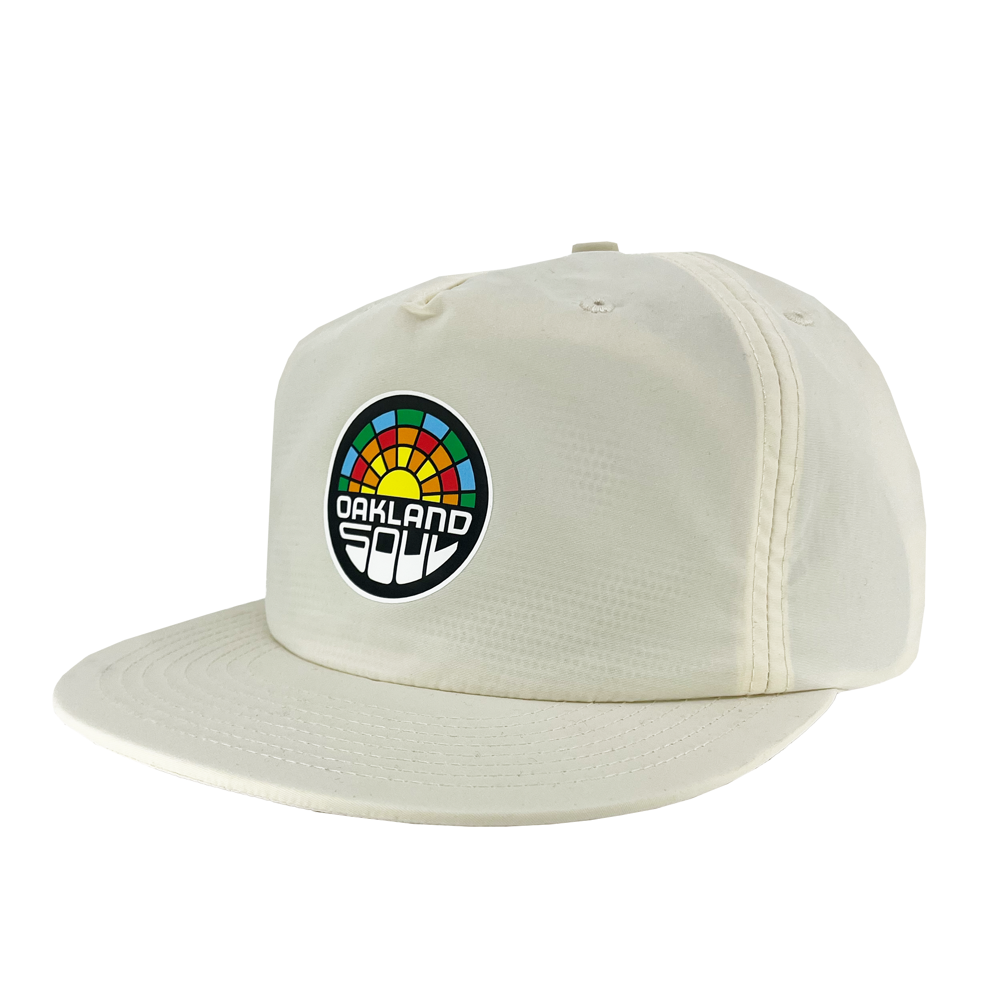 The Oakland Soul Surf Cap is a cream-colored baseball cap with a flat brim, featuring a colorful circular logo on the front. The logo displays a multicolored rainbow-like arc above the text "Oakland Soul," symbolizing the dynamic women's soccer team in the USL W-League, written in a bold, white, modern font against a black background.