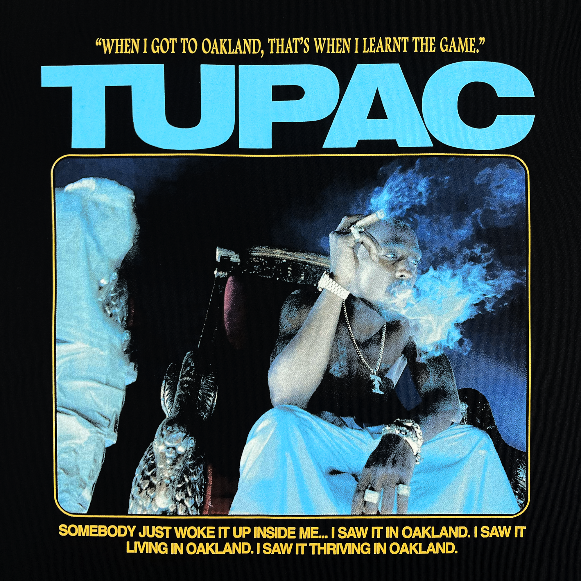 The Throne Tee by Oaklandish showcases a textured graphic of a figure in blue tones, relaxing with a cigarette on a throne-like chair. The text above reads, "When I got to Oakland, that's when I learnt the game," while below, the bold word "TUPAC" emphasizes how the hip-hop scene in Oakland influenced his life.