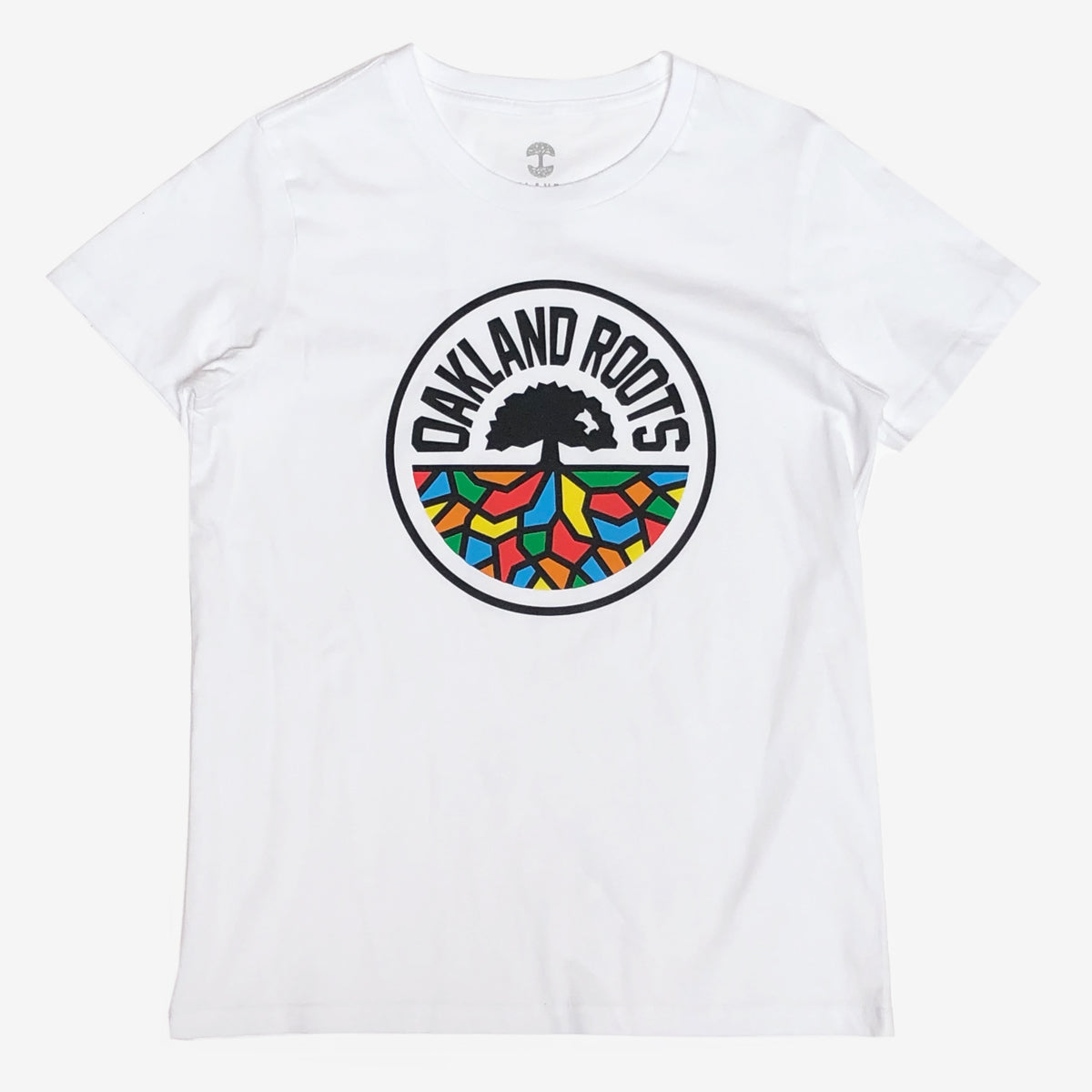 The Women's Oakland Roots SC Classic Tee is a white t-shirt that showcases a circular "OAKLAND ROOTS" logo. The logo features a black tree silhouette at the center with vibrant, multicolored roots beneath it, set against a semi-transparent white background. The outline and the "OAKLAND ROOTS" text are in black, capturing the essence of this sports club committed to social good.