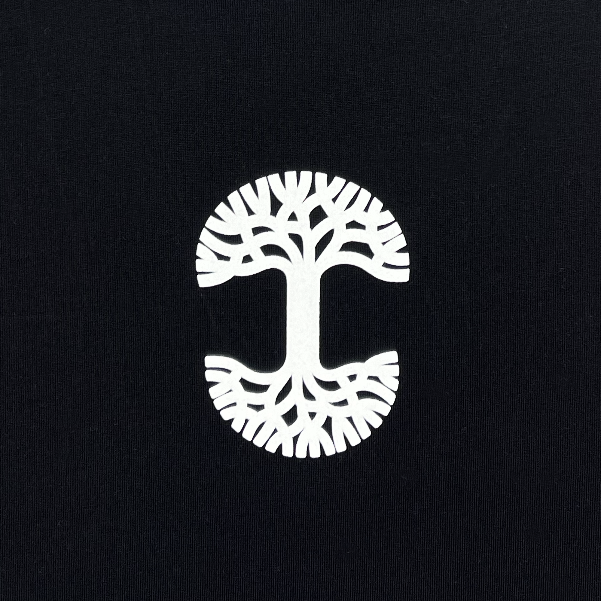 The "Who We Are and Who We Do it For Tee" by Oaklandish features a minimalist white tree design with symmetrical branches and roots, centered on a black background. The tree's evenly spread out branches at the top and mirrored roots at the bottom create a balanced and visually appealing aesthetic on this 100% cotton classic fit t-shirt, perfect for representing Oakland.